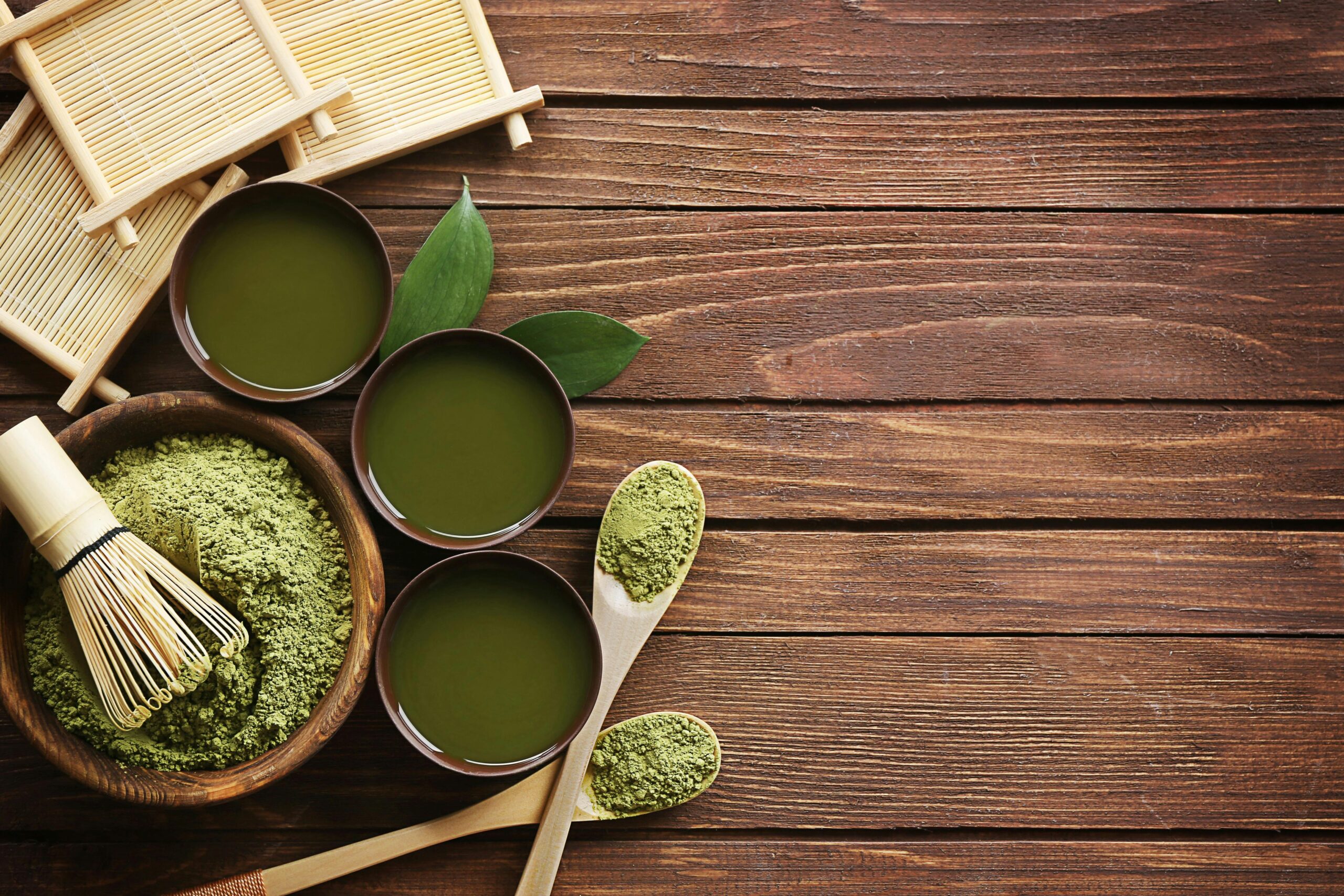 Top view of traditional matcha tea setup with utensils on a wooden table, showcasing a blend of culture and flavor.