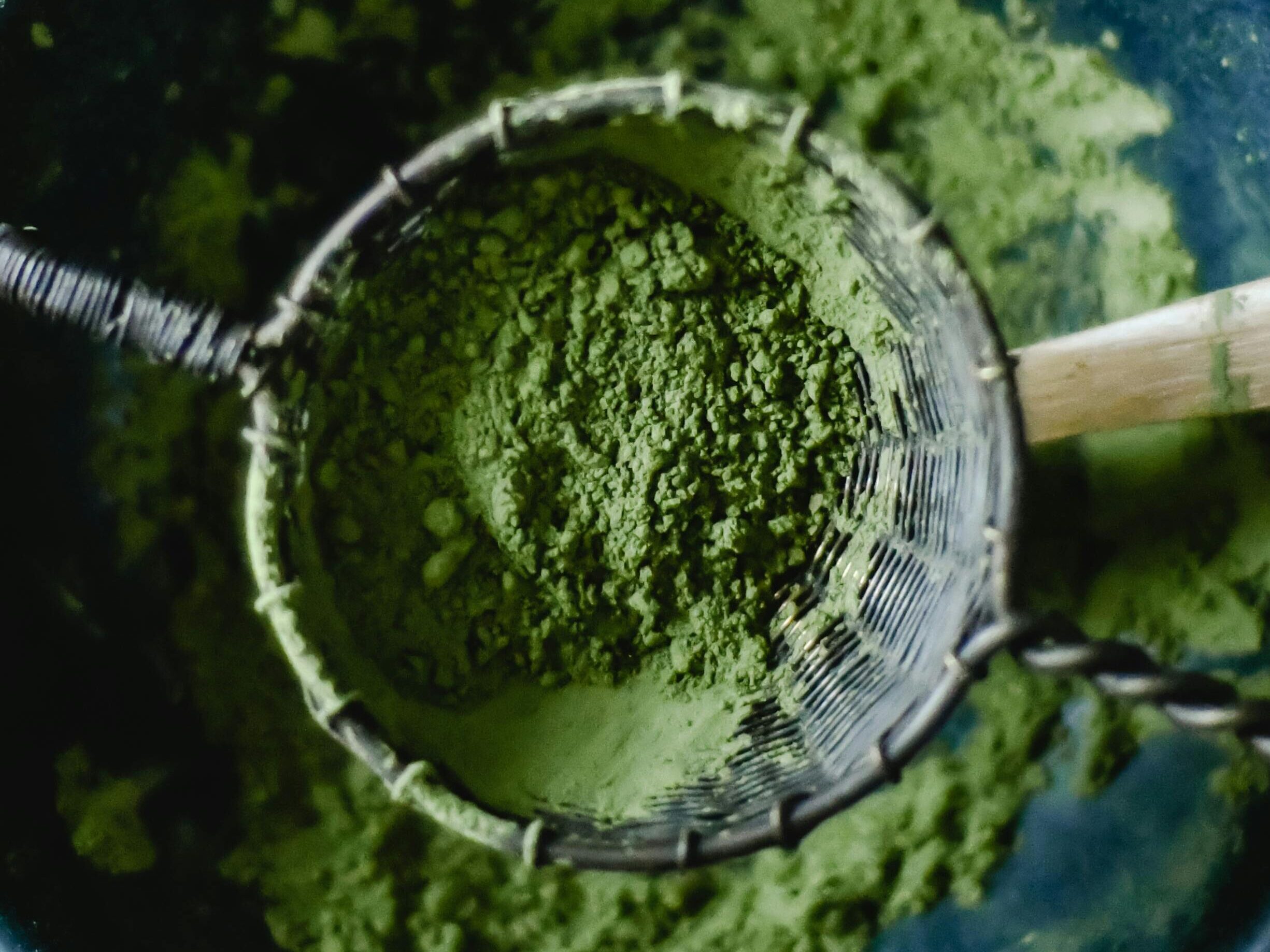 Green tea matcha powder in a sieve placed over a bowl, illustrating a healthy organic lifestyle.